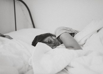 Mulher dormindo tranquilamente em uma cama com edredom branco